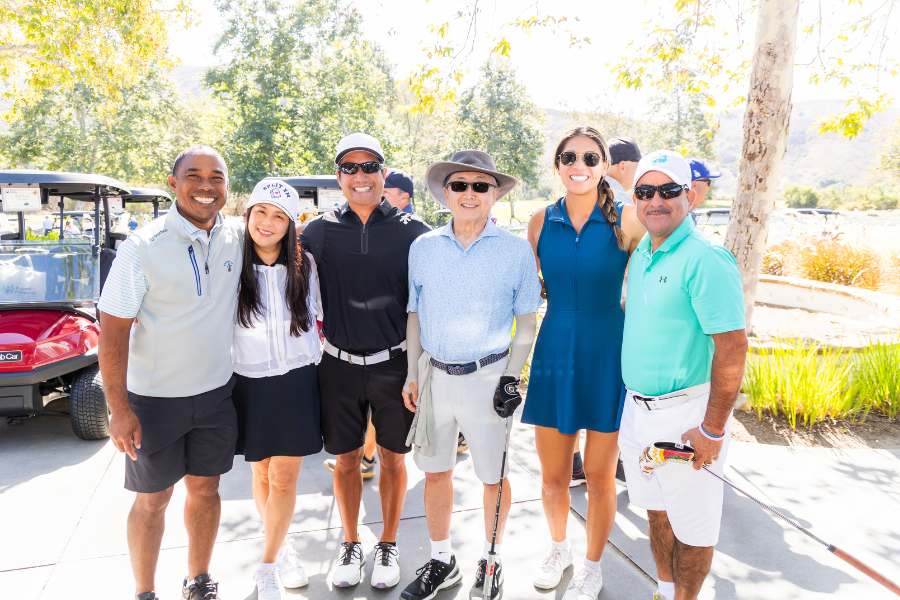 A group of men and women smiling in front of golf carts