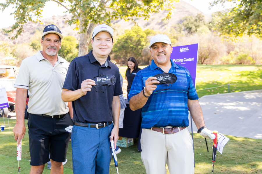 Two men smiling with golf clubs and blindfolds