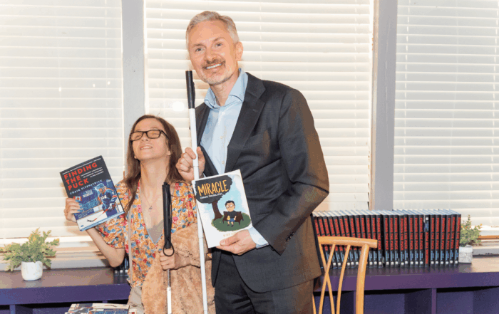 A man and woman pose holding books