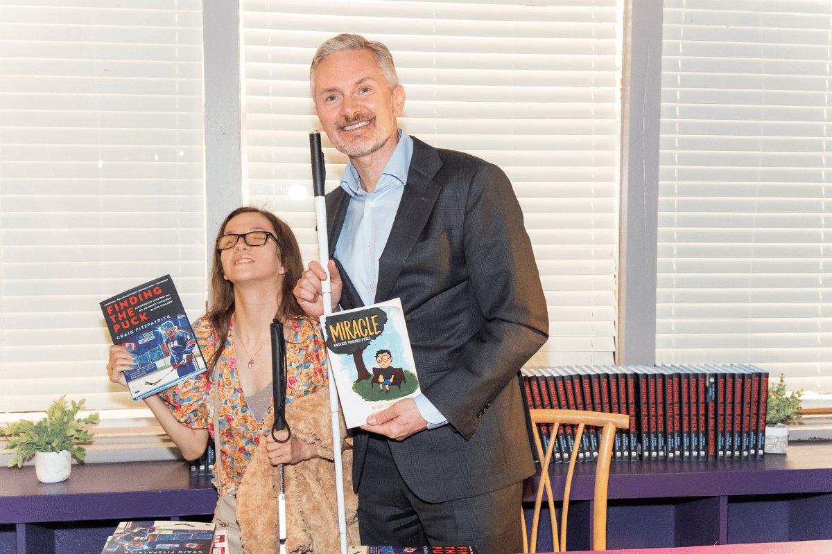A man and woman pose holding books