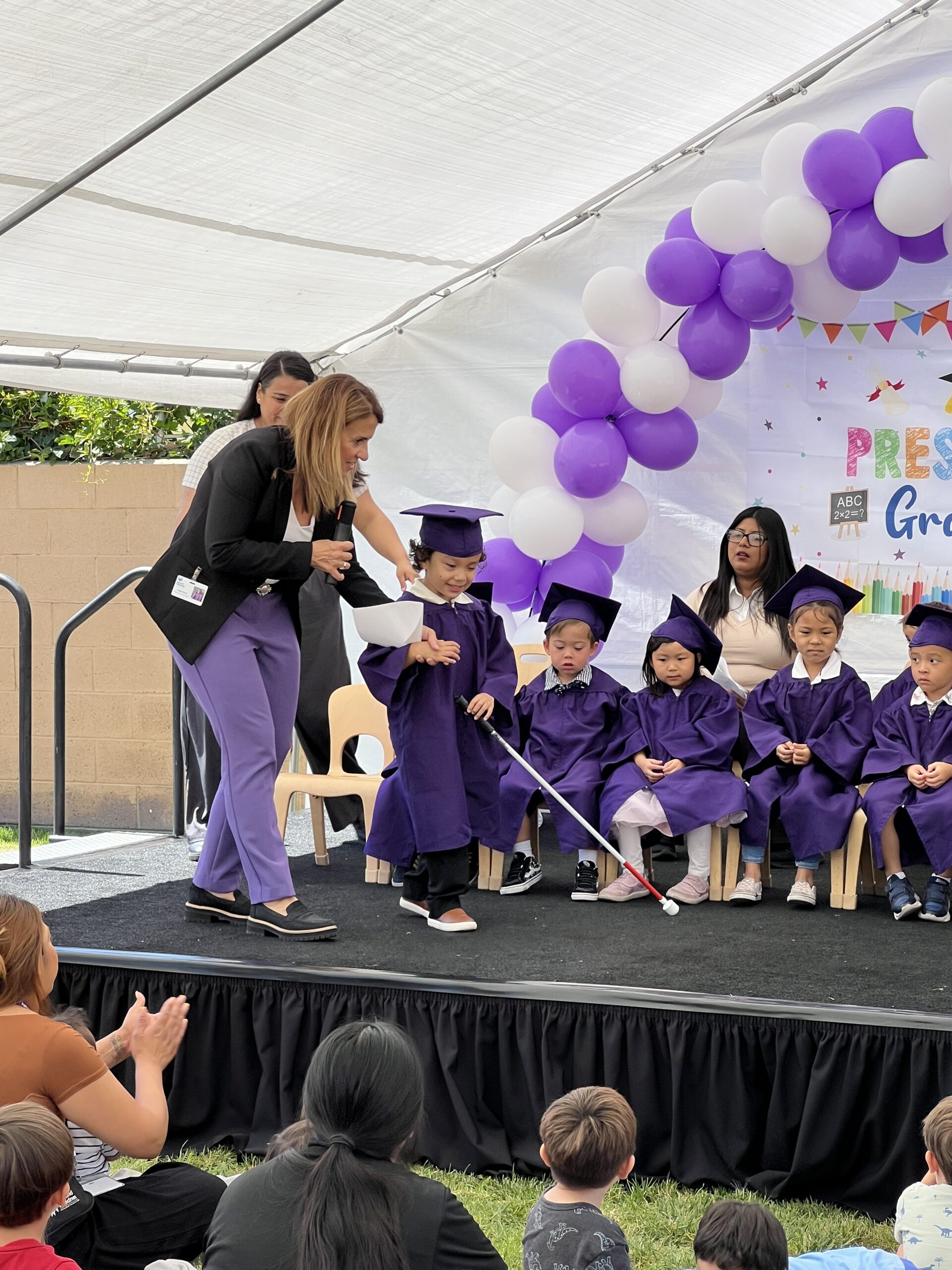 Children on stage in caps and gowns